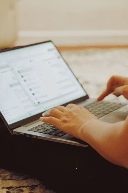 A person is using their smartphone to browse the SumUp Instagram profile, focusing on posts related to marketing strategies and business tips. In the background, a laptop displays a webpage about tools for business growth, suggesting a workspace or content creation environment. This image highlights the use of social media for brand promotion, digital marketing, and business engagement, making it relevant for content creators, marketers, and entrepreneurs.